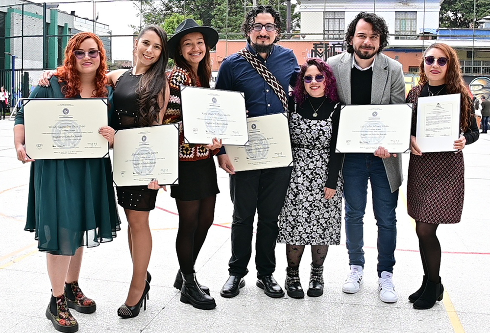 Fotografía de recién graduados de la Universidad Pedagógica Nacional en las instalaciones de la Calle 72. Los egresados muestran con orgullos sus diplomas