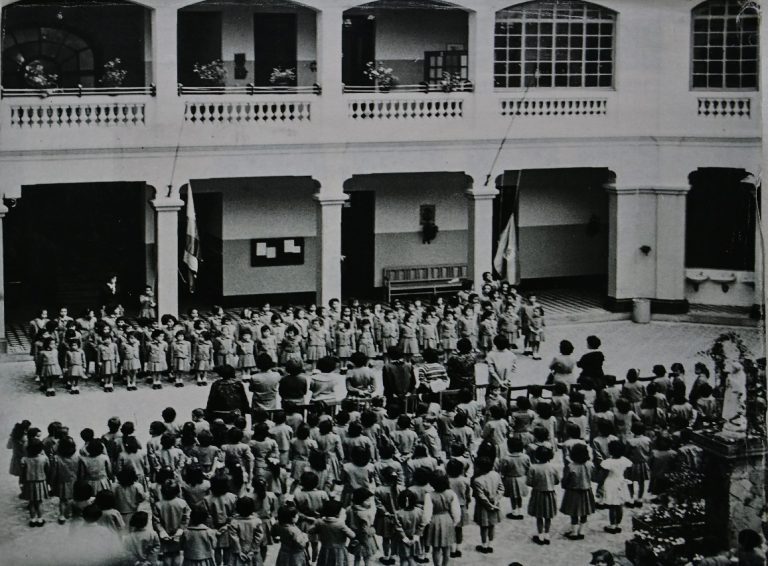 Fotografía histórica UPN a blanco y negro, escolares y directivos en formación ante un evento de la institución